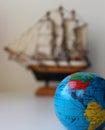 Small Globe With Mapped Travel Routes And Defocused Masted Ship Toy On Background Royalty Free Stock Photo