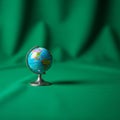 A small globe with a silver stand is set against a textured green Royalty Free Stock Photo