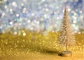 A small gold Christmas tree on a gold surface with defocused background with bokeh lights. Royalty Free Stock Photo
