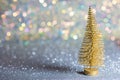 A small gold Christmas tree on a silver surface with defocused background with bokeh lights. Royalty Free Stock Photo