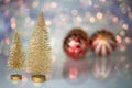 A small Golden Christmas tree on the glass surface with defocused background with bokeh lights and a red Christmas balls Royalty Free Stock Photo