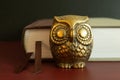 A small golden owl figure in front of a book.