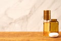 Small golden perfume flask and brown cosmetic jar on the wooden table Royalty Free Stock Photo
