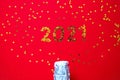 Small golden stars in the form of number 2021 a bottle of champagne on red background. Christmas, Xmas and New Year celebration, Royalty Free Stock Photo