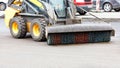 A small grader with a trailed nylon brush with hydraulics cleans the repaired section of the road from dirt