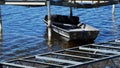 Small gray aluminum boat, used by dock installers to hold equipment, floats among lifts on a lake.
