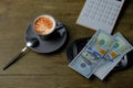 Small gray cup of coffee on a wooden table, metal money tray, american dollars banknotes, Restaurant bill, calculator, tip money Royalty Free Stock Photo