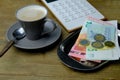 Small gray cup of coffee on a wooden table, metal tray for money, euro banknotes and coins, calculator, Restaurant bill, tip money Royalty Free Stock Photo