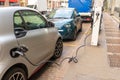 Small gray and green electric car charging on a city street Royalty Free Stock Photo