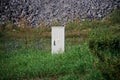 Small gray transformer cabin among green grass, wild flowers and gray stones