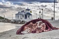 A small greek chapel over sea and small bay under a dramatic sky on a Greek island Royalty Free Stock Photo