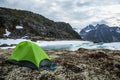 Small green backpacking tent with snowshoes outside. Overlooking partially frozen lake in spring time Royalty Free Stock Photo