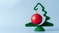 A small green Christmas tree with a hanging red ball on a blue background. New Year and Christmas card Royalty Free Stock Photo