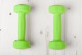 Small green dumbbells on wooden surface Royalty Free Stock Photo