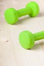 Small green dumbbells on wooden surface Royalty Free Stock Photo