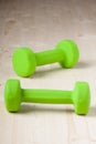 Small green dumbbells on wooden surface Royalty Free Stock Photo