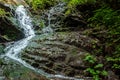 Small green forest waterfall in the cave mountains, cascades on a mountain river. The concept of active holidays, holidays Royalty Free Stock Photo