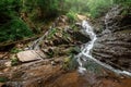 Small green forest waterfall in the cave mountains, cascades on a mountain river. The concept of active holidays, holidays Royalty Free Stock Photo