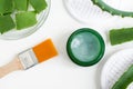 Small green jar with aloe vera healing balm salve, ointment, facial cream or hair mask and cosmetic brush.