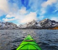 Small green kayak in bay fjord in the Lofoten Islands surrounded with snowy mountains and blue sky. Norway. Royalty Free Stock Photo