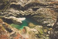 Small green pool surrounded by large rock covered in moss