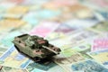 Small green tank on many banknotes of different currency. Background of war funding Royalty Free Stock Photo
