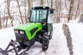 Small green tractor on snow path, winter and frost