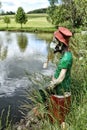 Small green water sprite wearing face mask sitting by the pond