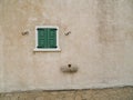 Small green window on plain stone wall