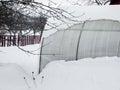 A small greenhouse covered with winter snow