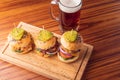 Small grilled burgers served to share with beer on rustic table Royalty Free Stock Photo