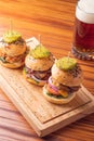 Small grilled burgers served to share with beer on rustic table Royalty Free Stock Photo