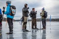 Small group of male ice skaters taking a break on a watery frozen lake. Royalty Free Stock Photo