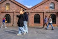 Small Group Of People Men Women Walking Past A Traditional Brick Building