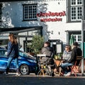 Small Group Of People Sitting Outside Talking And Drinking Coffee