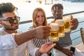 small group of young adult multiethnic friends toasting with three mugs of beer Royalty Free Stock Photo