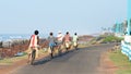 Small group of young and middle aged village people in remote coastal area returning home from work in bicycles. Cycle is the