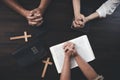 Small groups of Christians hold hands and pray together around a wooden table with bible pages and crosses. bible study group Royalty Free Stock Photo