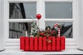 Window sill with Christmas decoration in red flower box. Small Christmas tree, red ball and red and white candy cane. Royalty Free Stock Photo