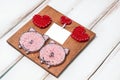 A small handmade panel with a picture of red hearts of a pair of pigs and a small postcard on white wooden background
