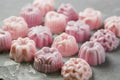 The small handmade soap is laid out in the form of a square in even rows on a concrete background. Lots of pink soap. Close-up