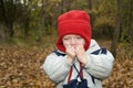 A small happy boy with red hat playing in leaves