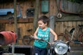 Small happy boy standing and holding the steering wheel old vintage damaged rusty motorbike