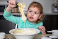 Small happy child cooking in kitchen. Little beautiful girl making dough for muffins at home. Royalty Free Stock Photo