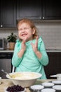 Small happy child cooking in kitchen. Little smiling girl making dough for muffins with berries. Royalty Free Stock Photo