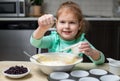 Small happy child cooking in kitchen. Little smiling girl making dough for muffins with berries. Royalty Free Stock Photo