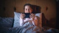 Small Happy Girl Watching Entertaining Videos on Smartphone in Bed Before Going to Sleep. Cute Kid Royalty Free Stock Photo