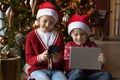 Small happy kids siblings using Christmas gifts electronic gadgets.