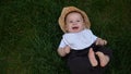 Small Happy Newborn child in summer panama hat Fall down laying on grass barefoot in Summer Sunny Day. Infant Kid Royalty Free Stock Photo