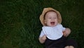 Small Happy Newborn child in summer panama hat Fall down laying on grass barefoot in Summer Sunny Day. Infant Kid Royalty Free Stock Photo